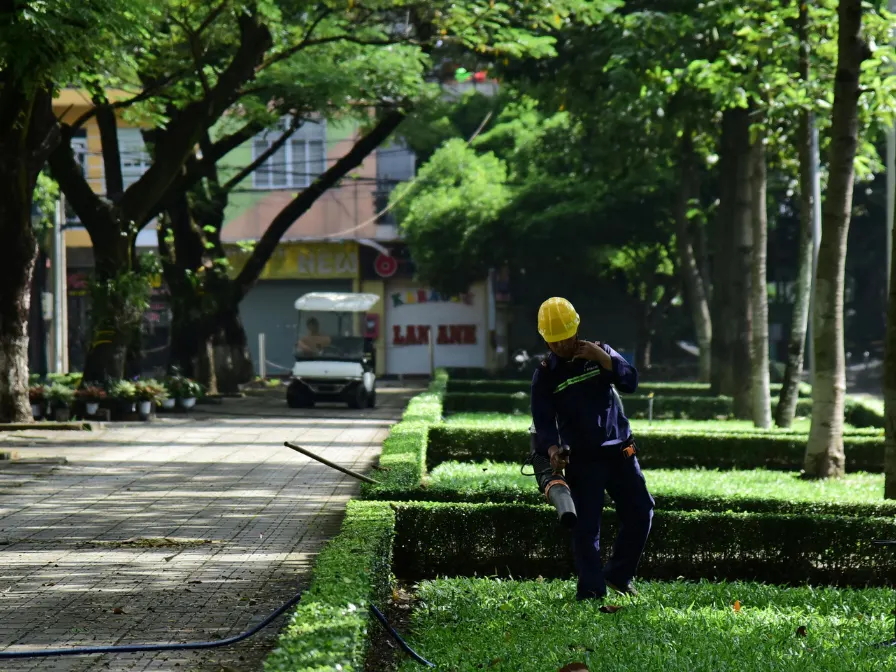 Southern Environmental maintenance professional using a leaf blower to clear an urban pedestrian path as part of end-of-year property maintenance in Central Florida.